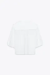 Camisa blanca de popelín con cuello bobo y mangas abullonadas 3/4. Cierre frontal con botones.