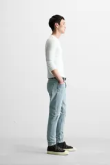 Pantalón de jean negro con corte skinny fit, cinco bolsillos, lavado con efecto roto y cierre frontal con cremallera y botón.