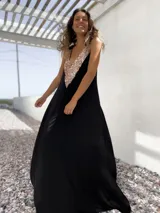 Vestido largo negro con escote en V y apliques de lentejuelas doradas en el corpiño.