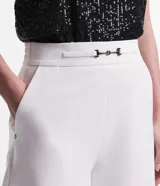 Short de vestir blanco de corte sastrero, con cintura alta, bolsillos laterales y detalle de hebilla metálica plateada en la cintura.