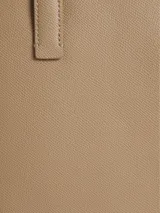 Mochila color tostado de cuero sintético granulado, con forma abombada, cierre superior con doble cremallera y tiradores con logo. Tiene asa de mano, correas ajustables, bolsillo exterior frontal y logo metálico plateado.