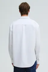 Camisa blanca de algodón Oxford con cuello americano, tapeta clásica, bolsillo superior abierto y canesú en la espalda. Mangas largas con puños abotonados y bajo levemente redondeado. Corte estándar.