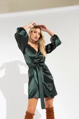 Vestido corto color fucsia de satén, con escote cruzado, mangas largas abullonadas y falda cruzada con lazo en la cintura.