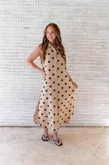 Camisola midi color beige con estampado de lunares negros, cuello camisero, sin mangas y abotonada al frente.