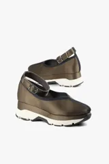 Zapato color marrón con base deportiva, pulsera al tobillo ajustable con hebilla metálica y puntera redondeada.