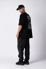 Remera negra oversize de algodón con cuello redondo y mangas cortas. Estampado pequeño en el frente y estampado grande en la espalda con la frase "Curbside Treasure".