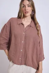 Camisa de lino color terracota, con cuello camisero, botones frontales y mangas amplias de tres cuartos.