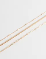 Collar corto dorado de tres capas con diferentes tipos de cadenas de metal.