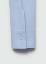 Camisa blanca entallada de popelina de algodón con cuello camisero, cierre frontal con botones y mangas largas con puños abotonados.