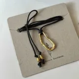 Collar con dije irregular dorado y cordón marrón ajustable.