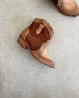 Bota corta de cuero vacuno color negro, con punta fina y tachas plateadas.