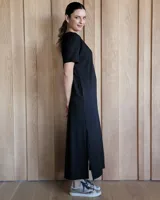 Vestido negro de corte recto, largo midi, con escote en V y mangas cortas.