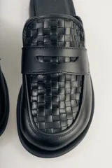 Mocasín mule de cuero negro con capellada tejida.