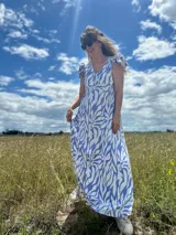 Vestido largo con estampado abstracto en tonos celeste y blanco, escote en V, mangas cortas con volados y corte holgado.