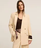 Blazer oversized color beige confeccionado en viscolino, con solapas en el cuello, botones delanteros y solapas delanteras que simulan bolsillos.