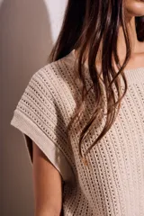 Chaleco de punto calado color beige, con cuello redondo y sisas amplias.