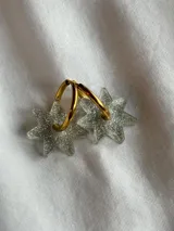 Par de aros dorados con forma de estrella negra.