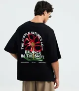 Remera de algodón negra, corte oversized, con estampa frontal de una flor estilizada en tonos rojo, amarillo y verde, y el texto "Balance ESTD. 1995" en blanco.