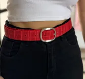 Cinto de cuero rojo con textura de croco y hebilla metálica.