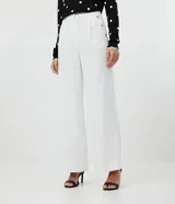 Pantalón wide leg blanco confeccionado en crepé, con botones dorados en los laterales, bolsillos y cierre con botón y cremallera.