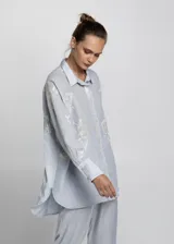 Camisa celeste de corte recto con bordados blancos.