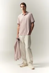Chomba de piqué de algodón color rosado, de corte clásico, con cuello clásico, tapeta de botones y mangas cortas con terminación acanalada.
