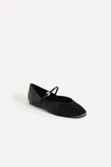 Zapato tipo bailarina color negro con efecto satinado, punta redonda y tira con hebilla ajustable.
