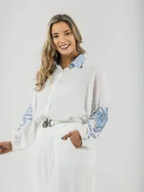 Camisa blanca de tela fresca con cuello camisero celeste y mangas abullonadas con apliques en denim celeste.