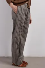 Pantalón de vestir de lino y viscosa color gris con rayas verticales marrones, corte sastrero y pinzas delanteras.