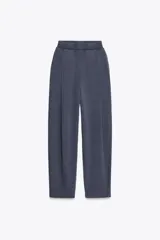 Pantalón color arena de tiro medio con cintura elástica, bolsillos laterales ocultos y pinzas en el delantero.