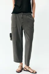Pantalón gris oscuro de tiro alto con cintura elástica, bolsillos delanteros y falsos bolsillos con solapa en la espalda. Cierre frontal con cremallera y botón.
