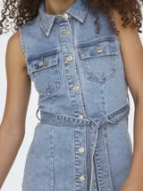 Vestido camisero de denim celeste, sin mangas, con cuello camisero, cierre frontal con botones y cinturón de lazo en la cintura.