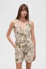 Mono corto sin mangas, entallado, con cuello en V y cierre frontal de botones. El tejido es de lino y viscosa con estampado tropical en tonos verde oliva sobre fondo beige claro. Incluye cinturón de lazo a juego.
