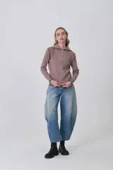 Sweater de punto acrílico con cuello alto y cierre frontal parcial. Presenta detalles de pespuntes en contraste en la unión de las mangas y en el ruedo, con diseño de manga larga.