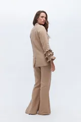 Conjunto de blazer y pantalón acampanado color rojo. El blazer es de corte clásico con solapas y un botón, y tiene volados en las mangas. El pantalón es de tiro alto y pierna acampanada.
