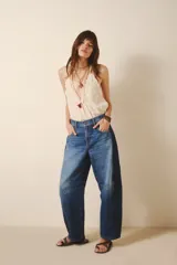 Pantalón jean de tiro alto, corte amplio y pierna ancha con parches en diferentes tonos de azul.