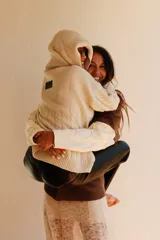 Buzo de tejido de punto color crudo, con cuello amplio que puede usarse caído sobre los hombros, mangas largas con trenzas de ochos y cuerpo con punto arroz.