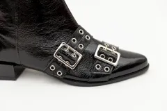 Bota corta de cuero charol color borgoña con punta fina y taco cuadrado negro. Presenta apliques de hebillas plateadas con ojalillos.