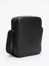 Bandolera Tommy Hilfiger negra con correa ajustable, cierre de cremallera, bolsillo interior abierto y logo metálico en el frente.