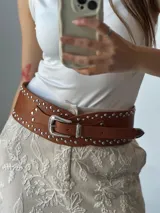 Faja ancha de cuero color marrón con tachas plateadas y hebilla metálica.