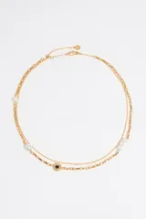 Collar dorado de doble cadena con dije de corazón negro con borde dorado.