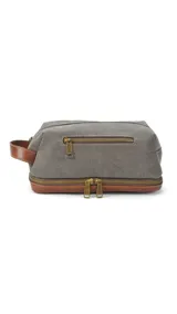 Neceser verde militar de tela canvas con detalles en cuero marrón. Tiene un bolsillo frontal con cierre, asa lateral y doble compartimento con cierre en la parte superior y en la base.