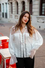Camisa color beige con encaje en la parte delantera y en las mangas, de corte holgado.