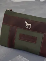 Sobre tipo cartuchera color borgoña, de lona con terminaciones en cuero marrón. Tiene cierre superior y aplique de cuero con el logo de la marca.