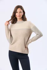 Buzo tejido con diseño de bloques de color en rosa, gris claro y beige. Posee un cuello alto y corte holgado.