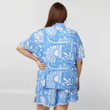 Conjunto de camisa de manga corta con cuello y short con cintura elástica, ambos con estampado de motivos marinos en blanco sobre fondo celeste.