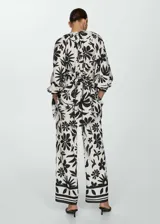 Pantalón wide leg de viscosa con estampado floral en blanco y negro. Tiene cintura elástica, dos bolsillos laterales y diseño largo.