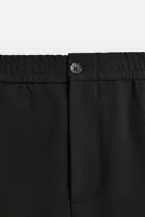 Pantalón negro de corte regular, confeccionado en tejido con viscosa, con cintura elástica, bolsillos frontales y trasero de vivo.