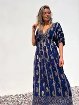 Vestido largo azul con estampado de cachemir dorado, escote en V, mangas cortas y cintura imperio con cordón ajustable.