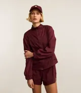 Campera deportiva rompevientos color bordó, con cuello alto, cierre frontal con cremallera, puños elastizados y recortes con hilo reflectante.
